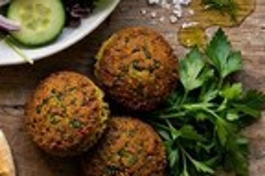 A close-up of falafel and parsley on a wooden table, enlarged normally